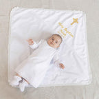 Baby in personalized linen baptism gown with embroidered blanket