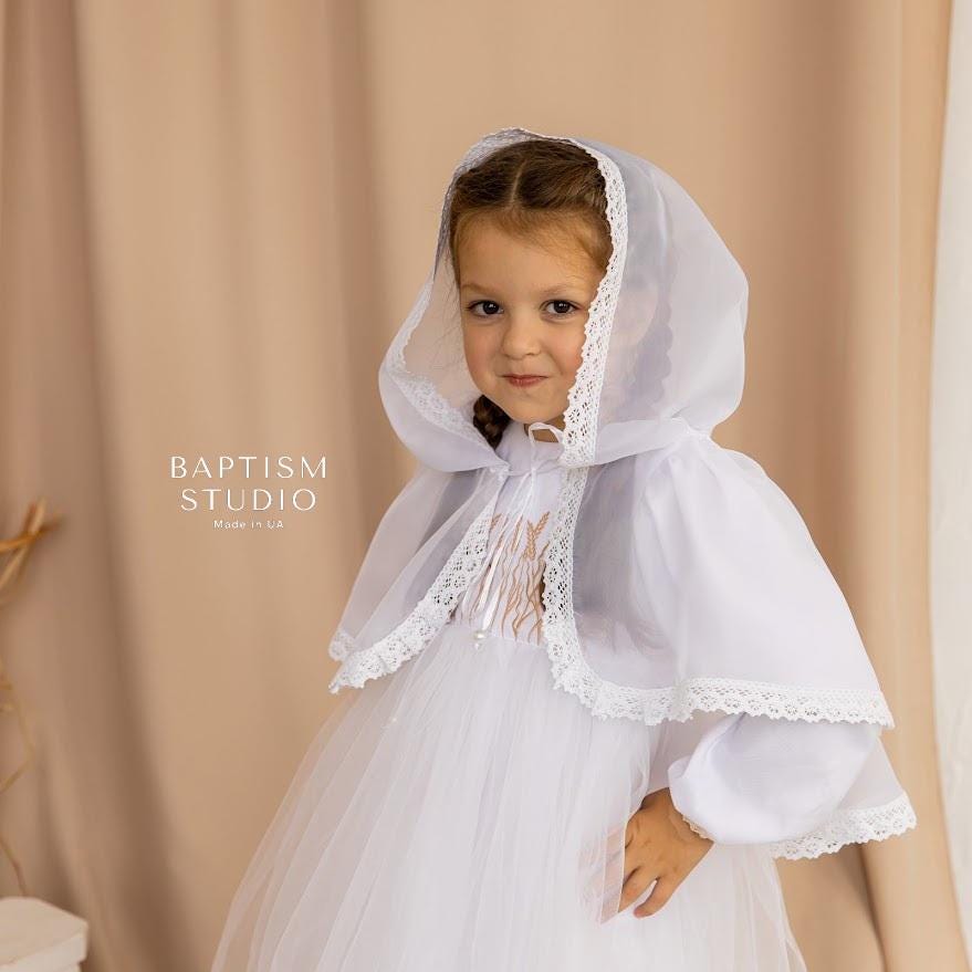 Little girl in white baptism veil with lace trim